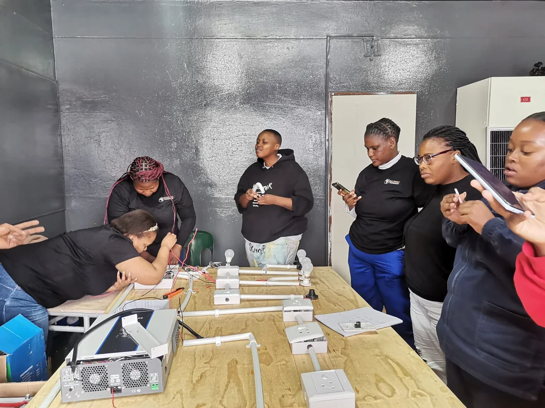 Learners practising electrical work on a training board