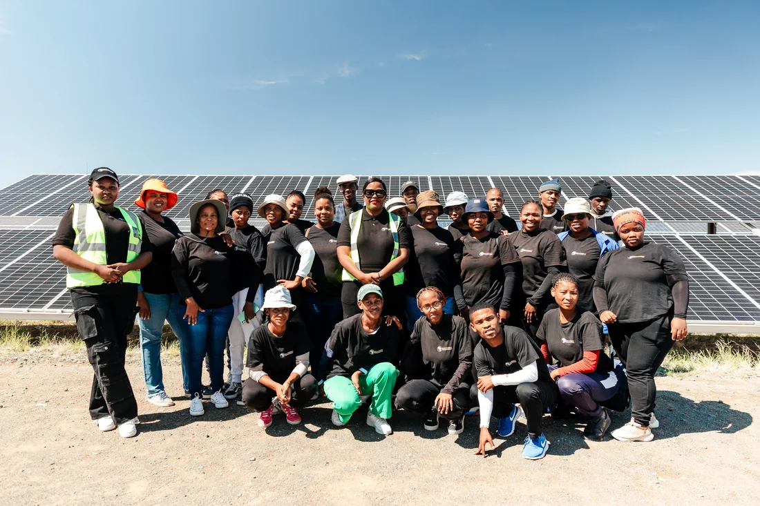 Solar photovoltaic service technician learners beside solar panels